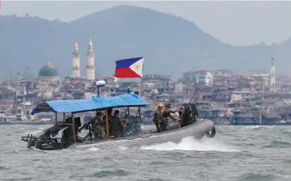  ?? AP FOTO ?? PATROL. Philippine Navy commandos aboard a gunboat patrol the periphery of Lake Lanao as smoke rises from the “Main Battle Area” where pro-Islamic group militants are making a final stand amid a massive military offensive of Marawi City.