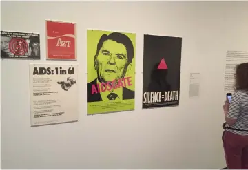  ??  ?? A patron looks at Silence=Death Project(1987- offset lithograph) during an exhibition at the Met Breuer, Metropolit­an Museum of Art. (Right) A woman takes a photo of Untitled (Vince Foster 1994) by Cady Noland. (Bottom right) A patron stands next to Peach Oswald (2001) by Wayne Gonzales. — AFP photos