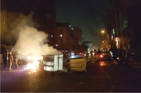  ?? (Reuters) ?? PROTESTERS BURN trash on the streets of Tehran.