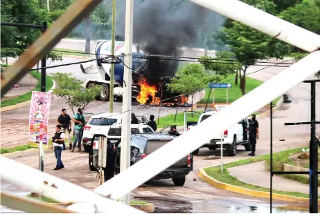  ?? Photo — Reuters ?? Cartel gunmen are seen near a burning truck during clashes with federal forces following the detention of Ovidio in Culiacan, Sinaloa state, Mexico.