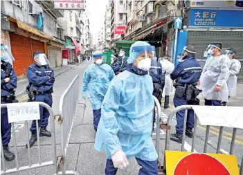  ?? — AFP photo ?? Police stand at the barrier of a blocked street as authoritie­s continue testing for the second day in the Jordan area of Hong Kong after thousands were ordered to stay in their homes on for the city’s first Covid-19 lockdown over the weekend.