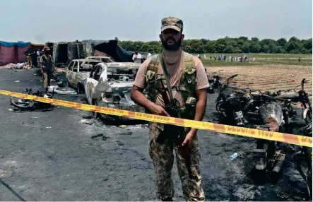  ?? Reuters ?? Soldado protege local da explosão de um caminhão-tanque que deixou ao menos 153 mortos em estrada do Paquistão