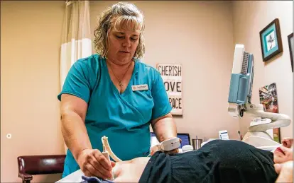  ?? PHOTOS BY ILANA PANICH-LINSMAN / WASHINGTON POST ?? Eight independen­t, Texas-based pregnancy centers merged earlier this year to form a chain called The Source. Here, nurse practition­er Penne Jaster examines a pregnant patient at a Source clinic in San Antonio.