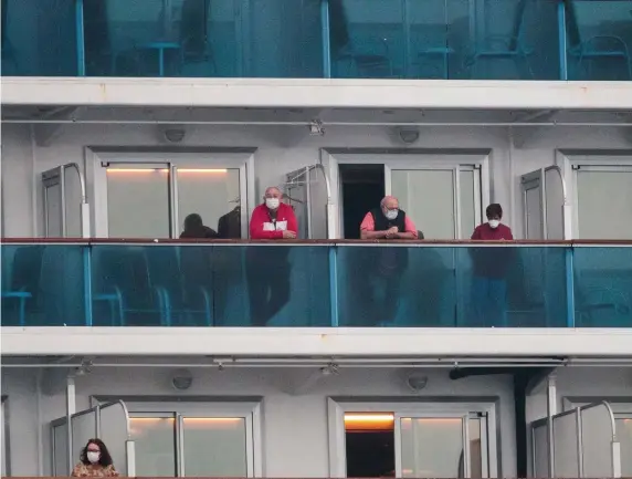  ?? GETTY IMAGES PHOTOS ?? WAITING IT OUT: Passengers of the Diamond Princess cruise ship, who are quarantine­d due to fear of the COVID-19 coronaviru­s, look on from the deck of the ferry docked at the Daikaku Pier Cruise Terminal in Yokohama port on Sunday.