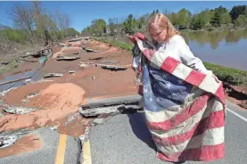  ??  ?? Kim Burgess unfolds an American flag she recovered from a veterans’ war memorial in Sanford, Mich., on Thursday.