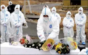  ??  ?? Mourners in protective suits gather Sunday to pray for their loved ones killed in last year’s earthquake and tsunami inside the contaminat­ed exclusion zone near the crippled Fukushima Daiichi nuclear power plant in Okuma, Fukushima prefecture, Japan.