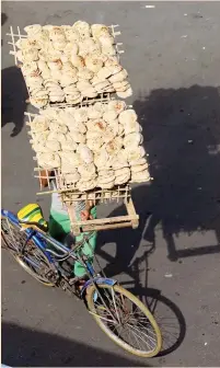  ?? (Mohamed Abd El Ghany/Reuters) ?? A BAKER (left photo) collects pitot as they come out of the oven at a bakery, and a bakery worker (right photo) rides a bicycle as he carries fresh pitot on his head, in Cairo earlier this month. Forty years after the Sadat-era bread riots establishe­d...