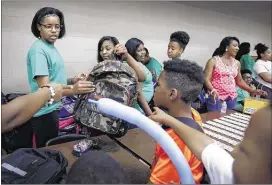  ?? MArk WeBer/The CoMMerCiAl AppeAl ?? Volunteers with ivy league help hand out book bags during the 16th annual Back to School health Fair and Family Festival at Whitehaven high School Saturday.