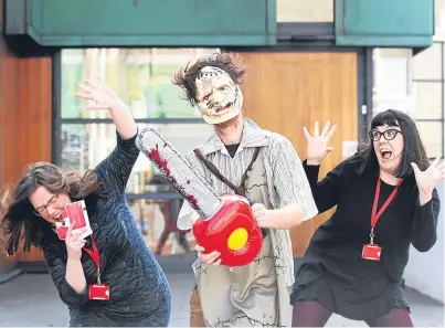  ?? Picture: Mhairi Edwards. ?? The Texas Chain Saw Massacre’s Leatherfac­e (Adrian Murray, DCA exhibition­s manager) can’t wait for the blood and gore to spill, while the fear is getting to communicat­ions officers Jenny Phin, left, and Meg Greenhorn.