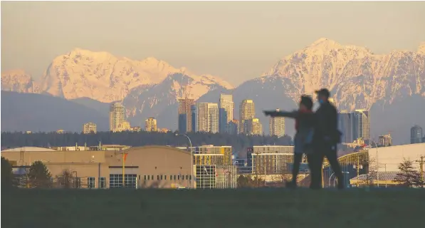  ?? ARLEN REDEKOP ?? A couple strolls into front of a vista of snow-capped mountains in Richmond on Monday.