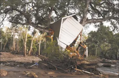  ?? Robyn Beck / AFP / Getty Images ?? A building uprooted by a massive mudslide is lodged in a tree in Montecito, Calif., in January. Climate change is already hurting the U.S. and global economies and its effects will get worse unless more drastic action is taken to cut carbon emissions, a major government report warned on Friday.