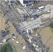  ?? The Yomiuri Shimbun ?? Vehicles and debris are seen scattered on and around railroad tracks after a levee broke following a downpour in Minami-Echizen, Fukui Prefecture, on Aug. 5.