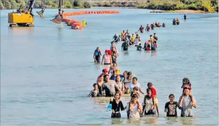  ?? EL PAÍS ?? Texas (EE. UU.). Un grupo de migrantes atraviesa el río Bravo en las cercanías de la zona de Eagle Pass.