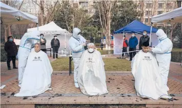  ?? CHINATOPIX ?? Hairdresse­rs in protective suits cut residents’ hair Sunday at a residentia­l block under strict lockdown in Xi’an.