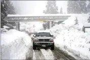  ?? JAE C. HONG / AP ?? A truck drives along snow berms in Running Springs on Feb. 28.