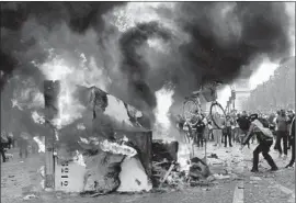  ??  ?? A BIKE is thrown onto a burning truck in Paris. Protesters were angered by rising fuel prices and accused President Emmanuel Macron of being out of touch.