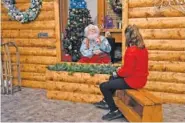  ?? AP PHOTO/JIM MONE ?? Santa, Sid Fletcher, sits behind a glass barrier as he hears Kendra Alexander of St. James, Minn., during her visit Nov. 15 at The Santa Experience at the Mall of America in Bloomingto­n, Minn.