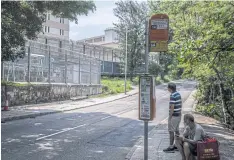  ?? ?? Two men wait at a bus stop across from Stanley Prison in Hong Kong. Officials have suggested that imprisoned pro-democracy activists are using sweets and other items to “solicit followers” behind bars.