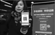  ?? XINHUA ?? A passenger shows her QR code to enter the metro station at the People's Square in Shanghai.