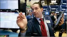  ?? RICHARD DREW — THE ASSOCIATED PRESS ?? Trader Tommy Kalikas works on the floor of the New York Stock Exchange, Thursday. A wave of buying sent U.S. stocks solidly higher on Wall Street Thursday, pushing the Dow Jones Industrial Average above the all-time high it closed at in January.