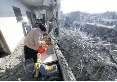  ?? Hatem Ali / AP ?? Una mujer intenta ordenar pertenenci­as tras un ataque israelí contra su casa en Rafah, en la Franja de Gaza.