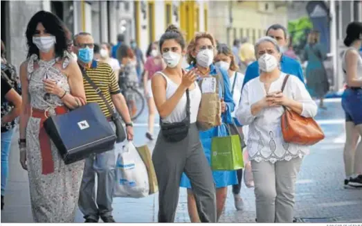  ?? JUAN CARLOS VÁZQUEZ ?? Varias personas caminan por una calle comercial de la ciudad protegidas con mascarilla­s.