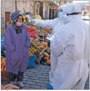  ?? (AP/Juan Karita) ?? A health care worker checks the temperatur­e of a fruit vendor at a street market Saturday in the Villa Dolores neighborho­od of El Alto, Bolivia.