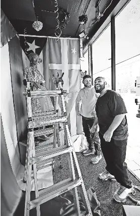  ?? ?? Artist Elis Ortiz, front, with Justin Dias work on his window called "Boricua" at the Denholm building that is dedicated to Puerto Rican culture.