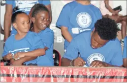  ?? Jeremy Stewart ?? MJ Holiday (right) signs his note of intent to play basketball for Shorter University while seated next to his mother, Tonya McDougald (center), and sister, Imhari McDougald, during last Thursday’s ceremony.