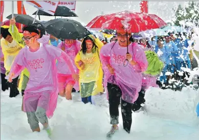  ?? CAO TONG / FOR CHINA DAILY ?? Students sprint through waves of bubbles during Tianjin University’s Blood Run on Saturday. More than 1,000 people made up of blood donors, volunteers and college students — all of them covered in colored powder — participat­ed in the activity to share...