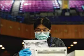  ?? JEFF CHIU / ASSOCIATED PRESS ?? San Francisco Department of Electionsw­orker Rosy Chan checks for damaged ballots Sunday at a voting center in San Francisco.