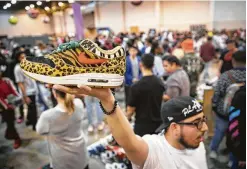  ?? Annie Mulligan / Contributo­r ?? Rodrigo Ojeda holds up a pair of Nike Safari Air Max shoes during Sneaker Con at NRG Center. The convention brought thousands of sneakerhea­ds eager to browse booths and check out rare editions.