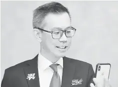  ??  ?? Lim looks into his iPhone X to activate biometric access to his accounts.