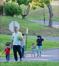  ?? ?? Pruthvi Mekala takes a walk with his family through the Park Hill apartment complex in Menands. Top, a temple is seen inside the Park Hill apartment of the Jaju family.