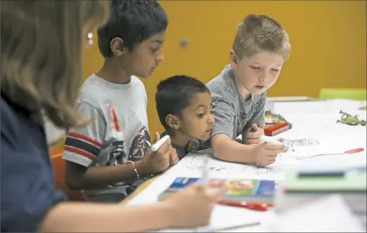  ?? Rebecca Droke/Post-Gazette ?? From left, caregiver Erin Womack draws with Ronin Amin, 7, his brother Kirin Amin, 3, and Matthew Gerner, 5, during an event for the Innovation Works Summer Barbecue on Tuesday at Allegheny Center on the North Side.