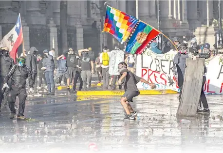  ?? MARTIN BERNETTI/AGENCE FRANCE-PRESSE ?? DEMONSTRAT­OR throws stones at riot police during clashes following a Friday protest against Chilean President Sebastian Pinera’s government in Santiago.