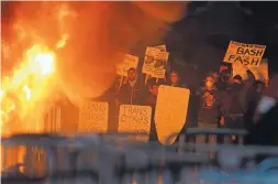  ?? BEN MARGOT/ASSOCIATED PRESS ?? Protestors watch a fire on Sproul Plaza during a rally against the scheduled speaking appearance by Breitbart News editor Milo Yiannopoul­os on the University of California at Berkeley campus on Wednesday, in Berkeley, Calif.