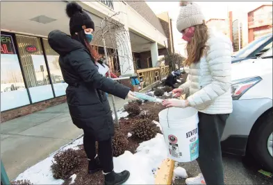  ?? Christian Abraham / Hearst Connecticu­t Media ?? Nicola LaRiccia places a discarded surgical mask into a bucket held by her daughter Liv, 13, as they join with volunteers from Mill River Wetland Committee and Fairfielde­rs Protecting Land and Neighborho­ods for a PPE cleanup at Fairfield Shopping Center's parking lot on Saturday. Over 35 people fanned out to several other locations like Home Depot and Stop & Shop to pick up litter and discarded PPE.