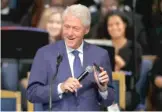  ??  ?? Former President Bill Clinton smiles as he plays a recording of Aretha Franklin on his phone during her funeral service Friday.