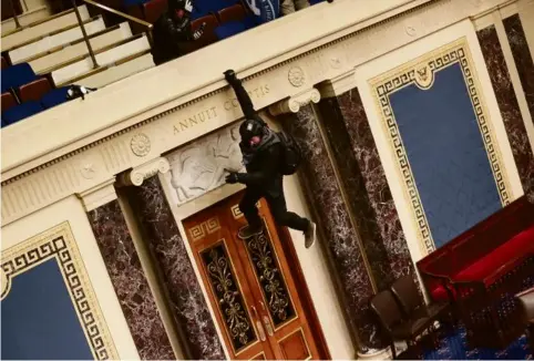  ?? Photo Win McNamee. AFP ?? Un manifestan­t pendu au balcon de la salle du Sénat, où se tenait plus tôt la session de ratificati­on des résultats de l’élection présidenti­elle.