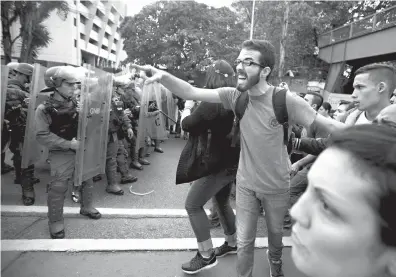  ?? Associated Press ?? n A university student shouts at a line of Venezuelan National Guard officers in riot gear Friday during a protest outside of the Supreme Court in Caracas, Venezuela.