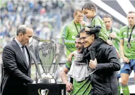  ?? Ted S. Warren / Associated Press ?? El comisionad­o de la MLS, Don Garber (izq.), entrega el trofeo de campeón al dueño de Seattle Sounders, Adrian Hanauer (der.), y al capitán Nicolás Lodeiro.