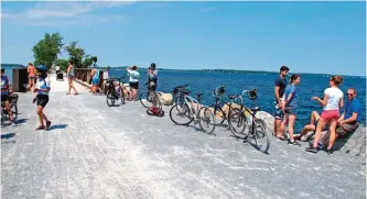  ??  ?? Bicyclists rest near a small bridge on the Island Line Trail bike path on an abandoned railroad causeway between the Vermont mainland and the Lake Champlain islands.