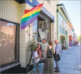  ??  ?? JOSEPH GEHA — STAFF PHOTOGRAPH­ER People chat outside The Iron Dog antiques store in the Niles district of Fremont last Sunday. Rae Steckler-Homorody, one of the shop’s owners, was verbally accosted by two men over her display of a rainbow flag in front...