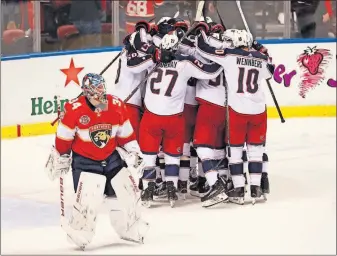  ?? [WILFREDO LEE/THE ASSOCIATED PRESS] ?? Blue Jackets players mob defenseman Seth Jones after Jones scored the winning goal 18 seconds into overtime against Panthers goaltender James Reimer, left.