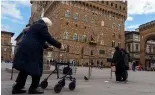  ?? ?? Une femme âgée se déplace à l'aide d'un déambulate­ur devant l'hôtel de ville du XIVe siècle, le Palazzo Vecchio (vieux palais), à Florence, en Italie, le jeudi 17 février 2022.