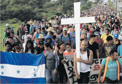  ?? Picture: Reuters ?? NEVER ENDING. Migrants, part of a caravan travelling en route to the United States, walk as they carry a Honduras flag and a cross in Pijijiapan, Mexico, on Sunday.