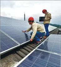  ?? YAO FENG / FOR CHINA DAILY ?? Technician­s at a power company check polysilico­n components in solar panels in Zhoushan, Zhejiang province.