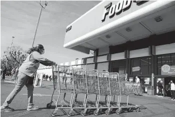  ?? CHRISTINA HOUSE LOS ANGELES TIMES ?? A grocery worker collects carts outside of a Food 4 Less store in Long Beach.