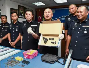  ?? — Bernama ?? Seized goods: Mohd Kamarudin showing the media a Browning gun and bullets found during the raid.